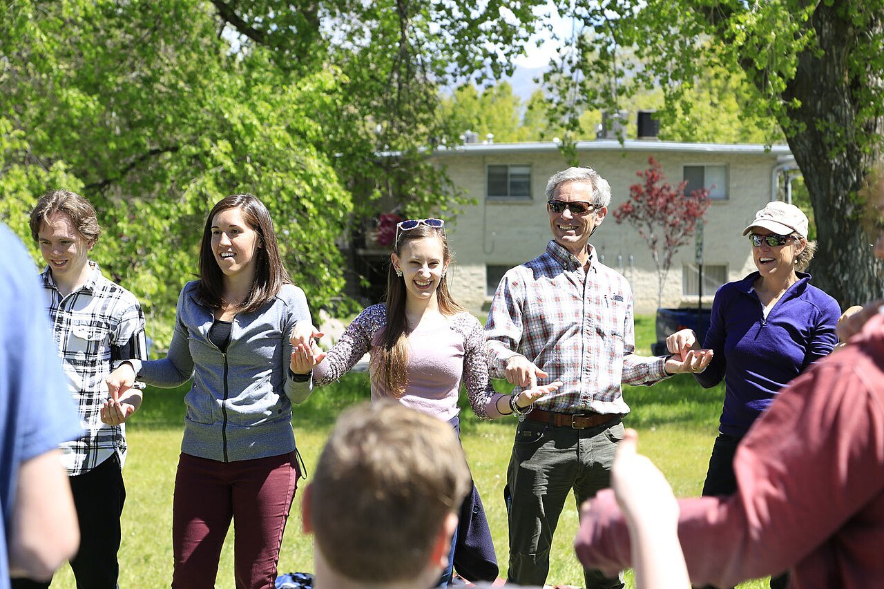 Un groupe d'adultes en cercle, main dans la main, dans un parc, lors d'un exercice de cohésion